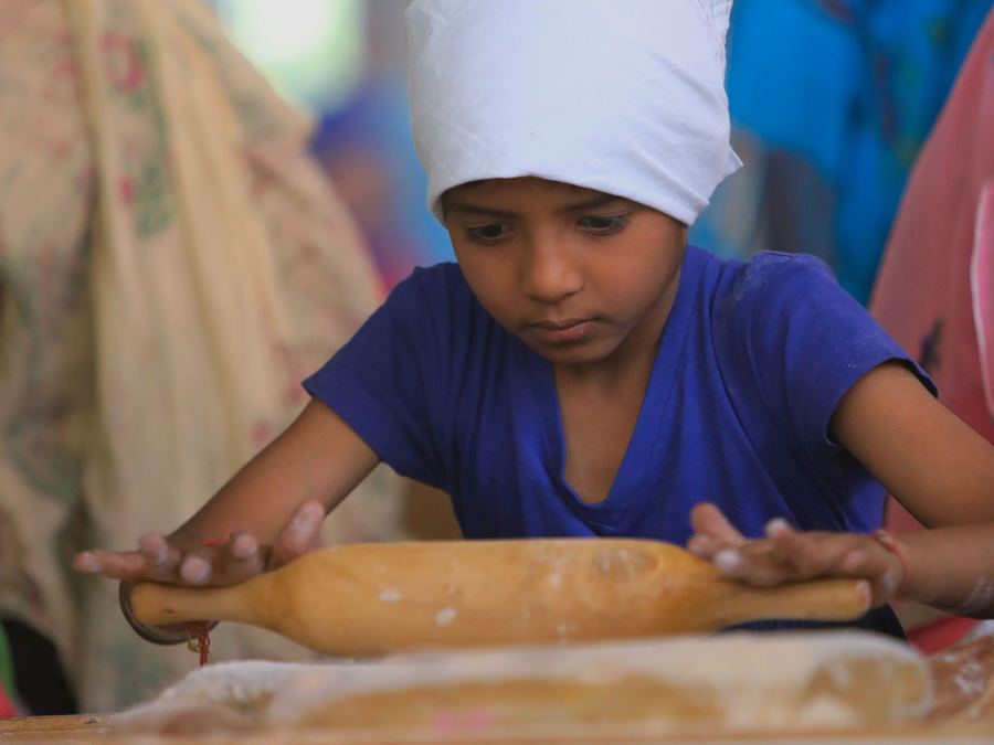 A boy rolling dough in a kitchen
